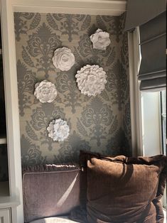 a couch in front of a wall with paper flowers on it