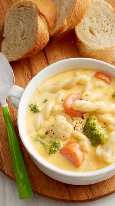 a bowl of soup with broccoli, carrots and noodles on a cutting board