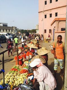 people are shopping at an outdoor market with many fruits and veggies on display