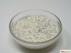 a glass bowl filled with white sauce on top of a table