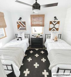 two twin beds in a small room with black and white rugs on the floor