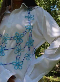 a close up of a person wearing a white shirt with blue flowers on the front