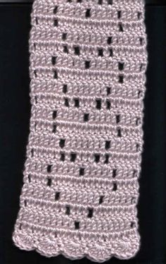 a crocheted piece of cloth hanging from a hook on a black background with white stitching