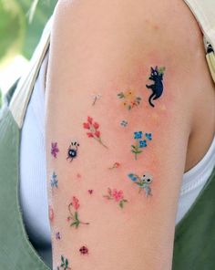 a woman's arm with flowers and a cat tattoo on the left side of her arm