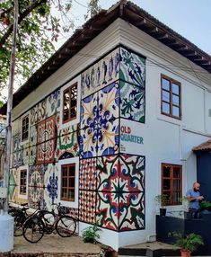 a white building with colorful tiles on it's side and a bicycle parked outside