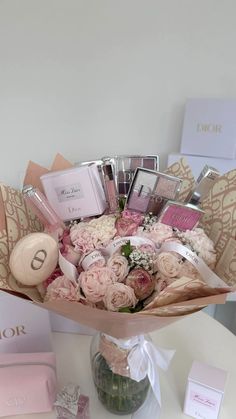 a vase filled with lots of pink flowers on top of a table next to other items