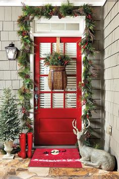 a red door decorated for christmas with greenery