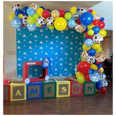 a birthday decoration made out of blocks with balloons and soccer balls on them, in front of a blue backdrop