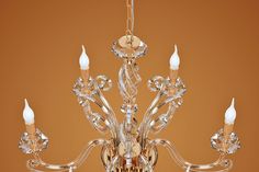 a crystal chandelier hanging from the ceiling in front of a brown wall with an orange background