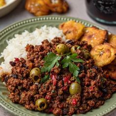 a green plate topped with meat and rice next to other foods on top of a table