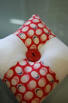 a red and white polka dot pillow with a button on it