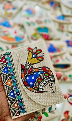 a hand holding a small wallet with colorful designs on it