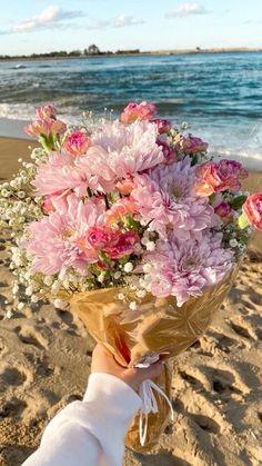 a person holding a bouquet of flowers on the beach