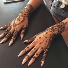 two hands with henna tattoos on them