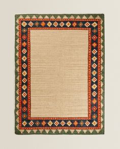 an area rug is hanging on the wall in front of a white wall with a blue and red border