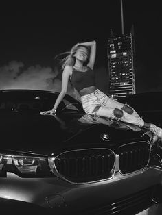 a woman leaning on the hood of a car