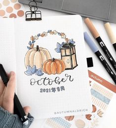 a person holding a pen and looking at an open notebook with the word october written on it