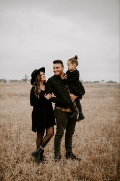 a man, woman and child standing in a field