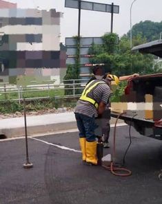 a man in yellow boots and safety gear washing a truck