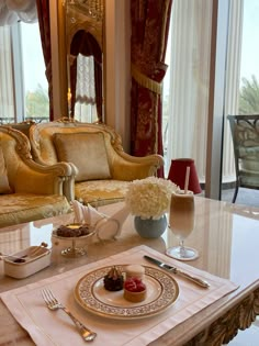 a table set for two in front of a fancy living room with couches and chairs