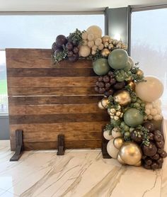 a wooden sign with balloons and greenery on it