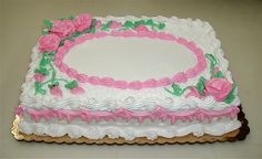 a large cake with white frosting and pink flowers on it's side, sitting on a table