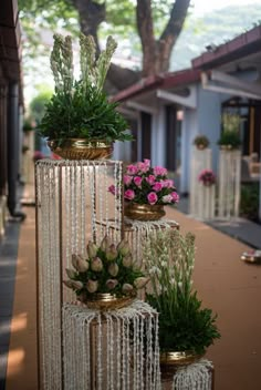 three tiered vases with flowers and greenery on the side of a road