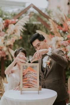 a bride and groom feeding each other cake at their wedding reception in front of an orange floral arch