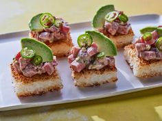 small appetizers are arranged on a white plate with pickles and olives