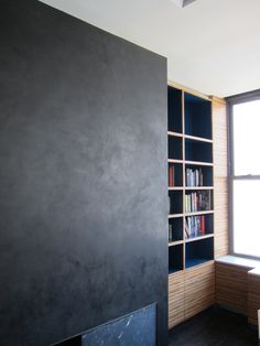 an empty room with bookshelves and a window in the corner, next to a book shelf