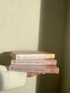 three books stacked on top of each other in front of a white wall and window