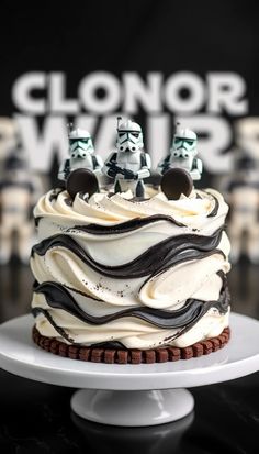 a star wars themed cake with white frosting and black icing, featuring stormtroopers on top