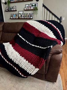 a couch with a blanket on top of it next to a brown leather chair in a living room