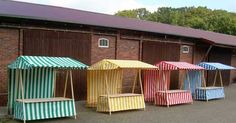 several different colored benches in front of a brick building with an awning on top