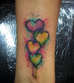 three heart shaped tattoos on the wrist and foot, painted in watercolor with spray paint