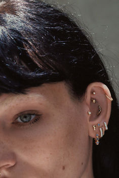 a close up of a person with ear piercings and an earring on their left side