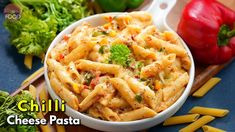 a bowl filled with pasta and vegetables on top of a cutting board next to peppers