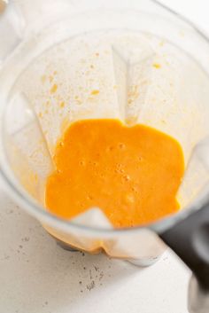 a blender filled with orange liquid on top of a counter