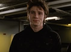 a young man standing in an empty garage