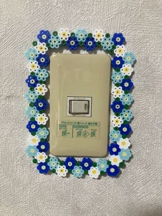 a decorative light switch cover with blue and white flowers in a frame on the wall