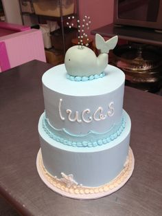 a three tiered cake decorated with a whale and the word lucas on it's side