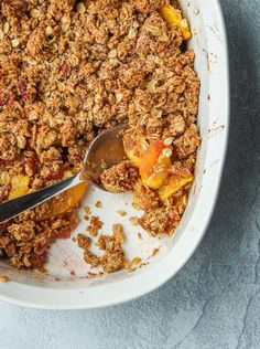 a white bowl filled with fruit and granola on top of a blue table cloth