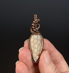 Fossilized coral cabochon wrapped in copper wire that has been oxidized and polished. The pendant comes in a jewelry gift box with a black waxed cord and small polishing pad. Size: 53 x 17 x 13 mm. 6 grams. Hand Forged Spiral Jewelry Gift, Unique Bronze Jewelry For Gifts, Unique Bronze Jewelry For Gift, Artisan Bronze Jewelry For Gift, Hand Wrapped Brass Jewelry Gift, Hand Wrapped Brass Jewelry For Gift, Unique Hand Wrapped Oval Pendant Jewelry, Handmade Copper Wire Jewelry With Oval Pendant, Artisan Copper Wire Jewelry As Gift