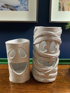 two ceramic cups with faces on them sitting on a table