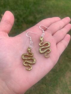 Each pair of sparkly snake earrings are handmade to order, therefore no two pairs are identical! However, I try to get as close as possible :) Made with sterling silver plated fishhook earrings (clear rubber backing included). Hypoallergenic & nickel-free. Each snake is approximately 1.5" long Made with epoxy resin and fine gold glitter ✨ Color may vary slightly. Thanks for visiting my shop! ⚡️ Handmade Snake-shaped Earrings As Gift, Snake-shaped Earrings With Ear Wire For Gift, Snake-shaped Earrings With Ear Wire As Gift, Fishhook Earrings, Earrings Handmade Dangle, Sparkly Jewelry, Snake Earrings, Retro Gifts, Glitter Earrings