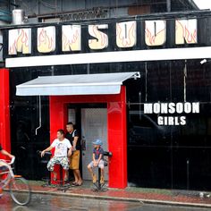 two children are standing in the doorway of a restaurant with their mom and dad on bikes