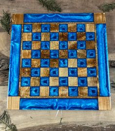 a blue and brown checkered board sitting on top of a wooden table next to pine branches