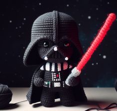 a crocheted darth vader is holding a red light saber