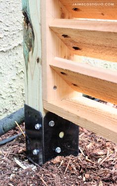 the bottom half of a wooden fence with metal studs and screws on it