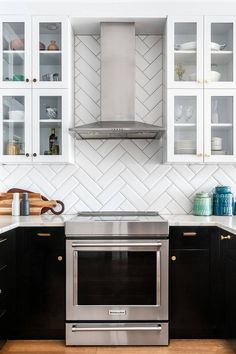 a kitchen with black cabinets and stainless steel stove top oven in the center, white subway backsplash